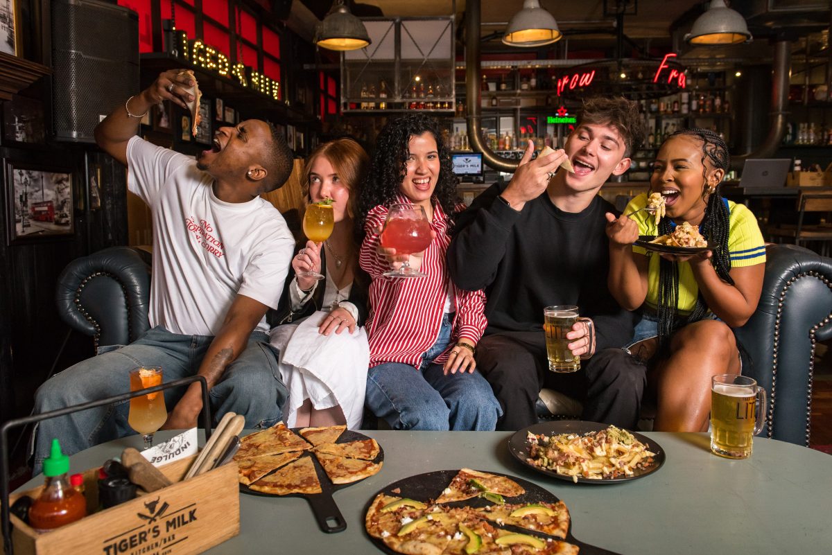 A group of friends enjoying a meal and drinks at Tiger's Milk
