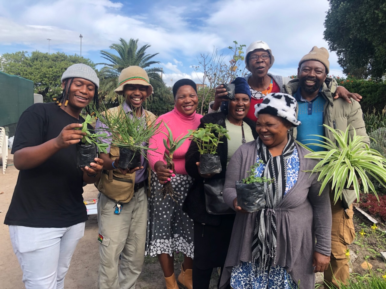 A group of friends each holding a plant
