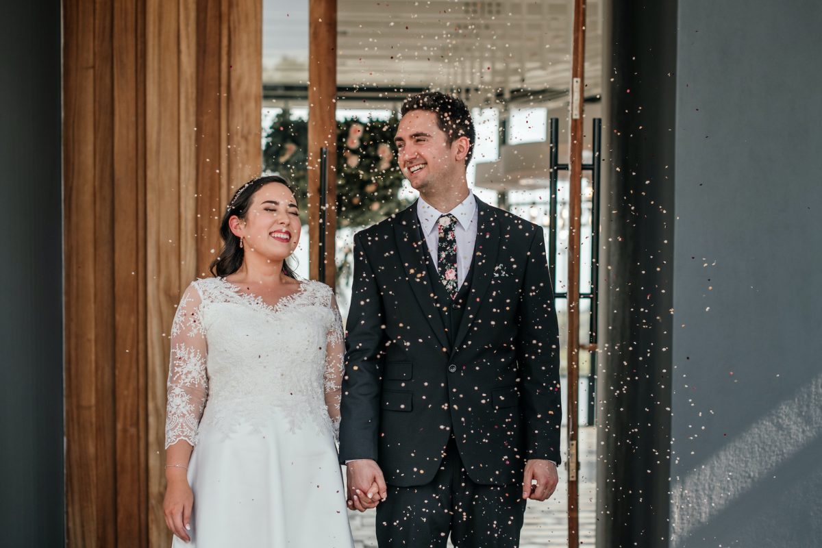 A bride and groom walking into their reception with confetti thrown at them